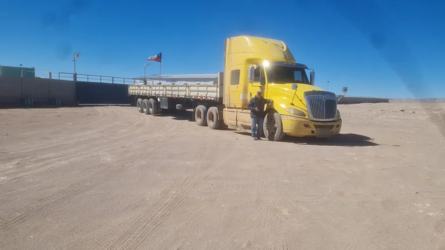 Tractocamión International amarillo con semirremolque cama plana en instalación del desierto