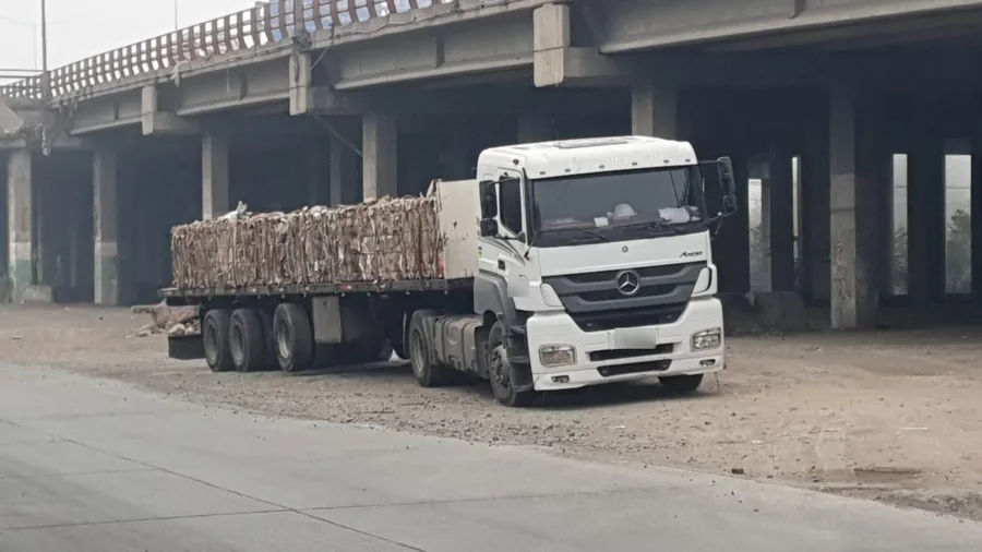 Camión Mercedes-Benz blanco con fardos de cartón sobre cama plana